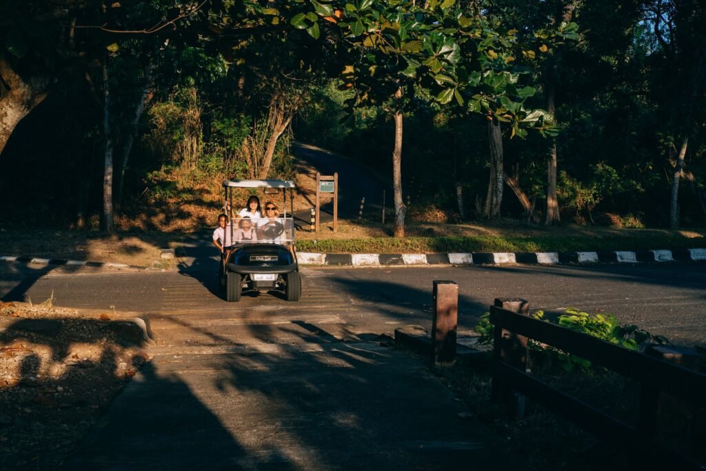 Family riding a golf cart on a tree-lined road in the evening